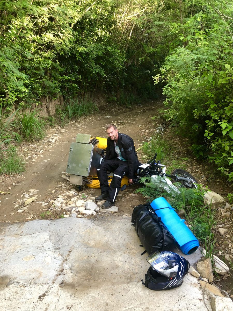 Motorradfahrer richtet Motorrad auf Schotterstraße in Kolumbien während erster Motorradreise durch Südamerika auf