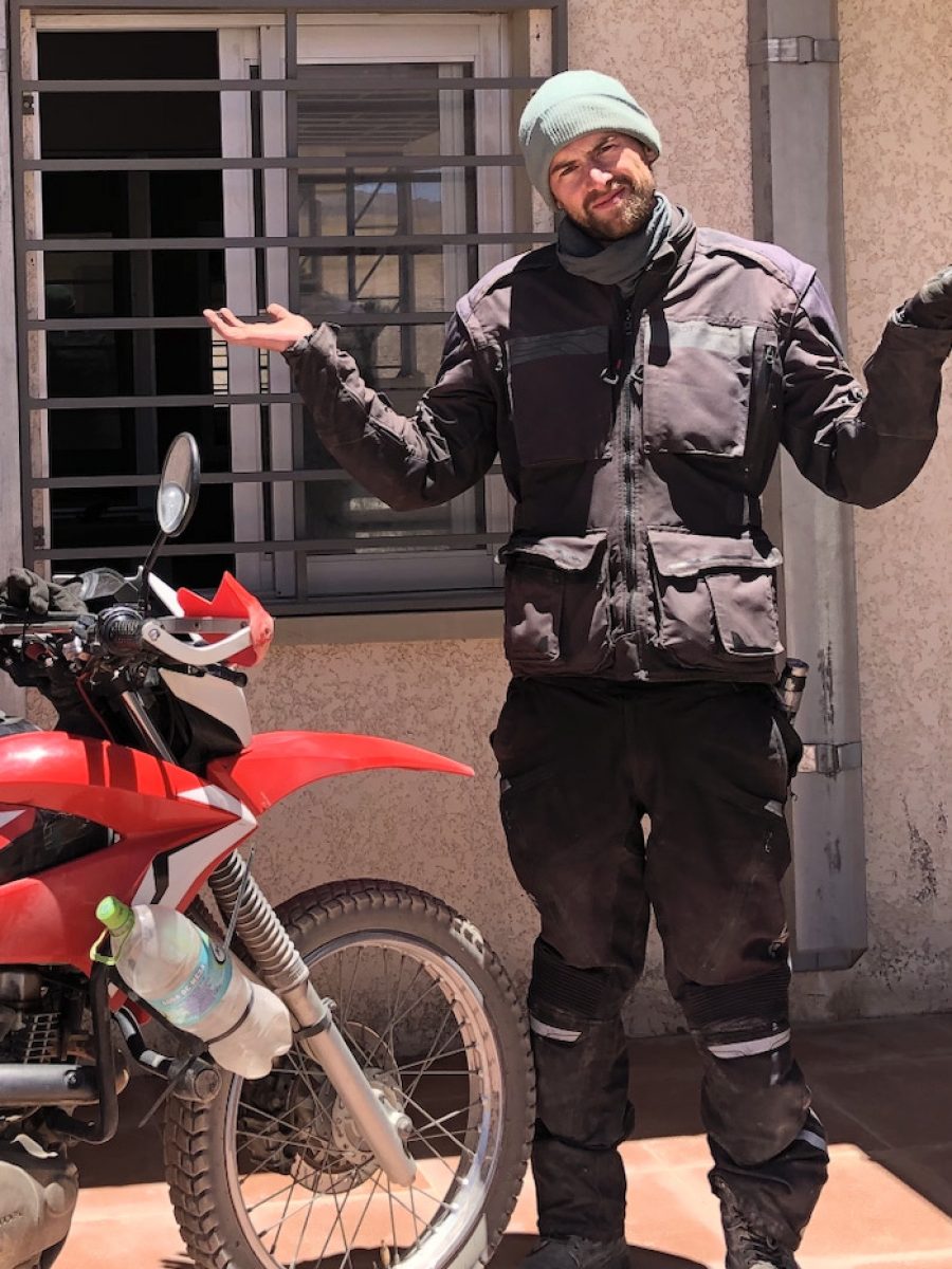 Motorradfahrer auf Motorradreise in Südamerika vor geschlossenem Grenzübergang in Bolivien mit Reiseenduro