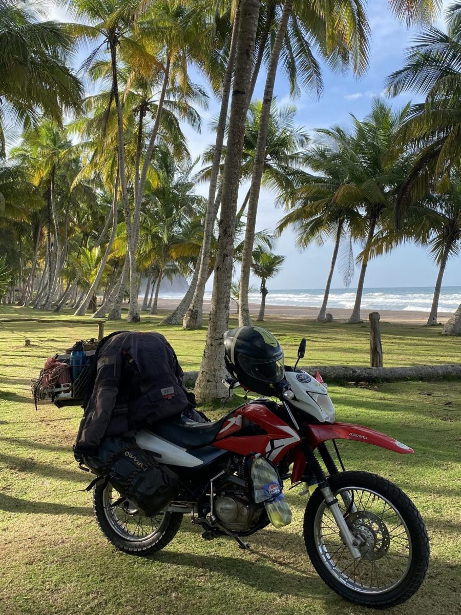 Motorrad an Palmenstrand in Kolumbien mit Meer im Hintergrund auf Motorradreise durch Südamerika