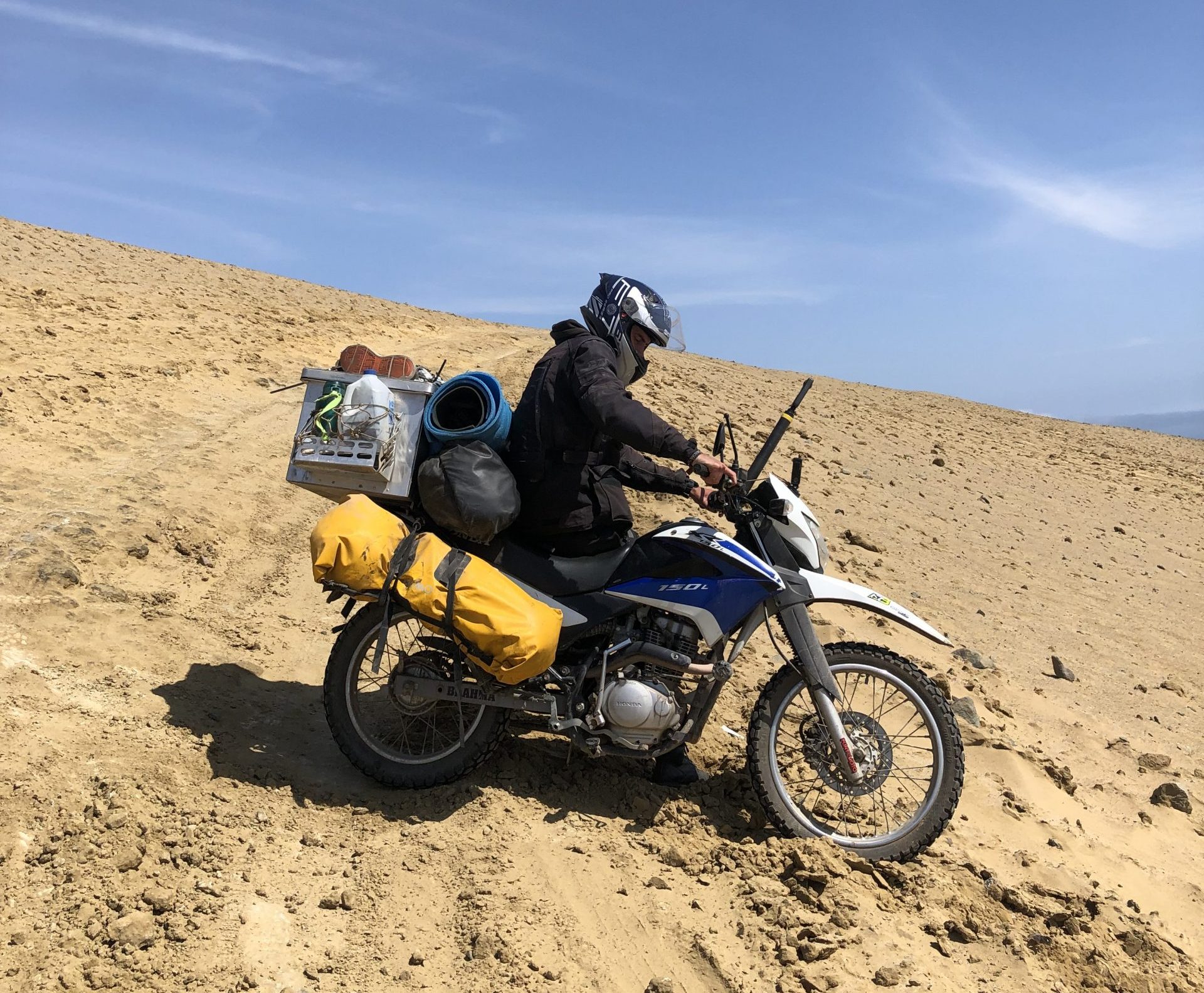 Motorradfahrer steckt im Sand an Hang in Südamerika fest während Motorradreise