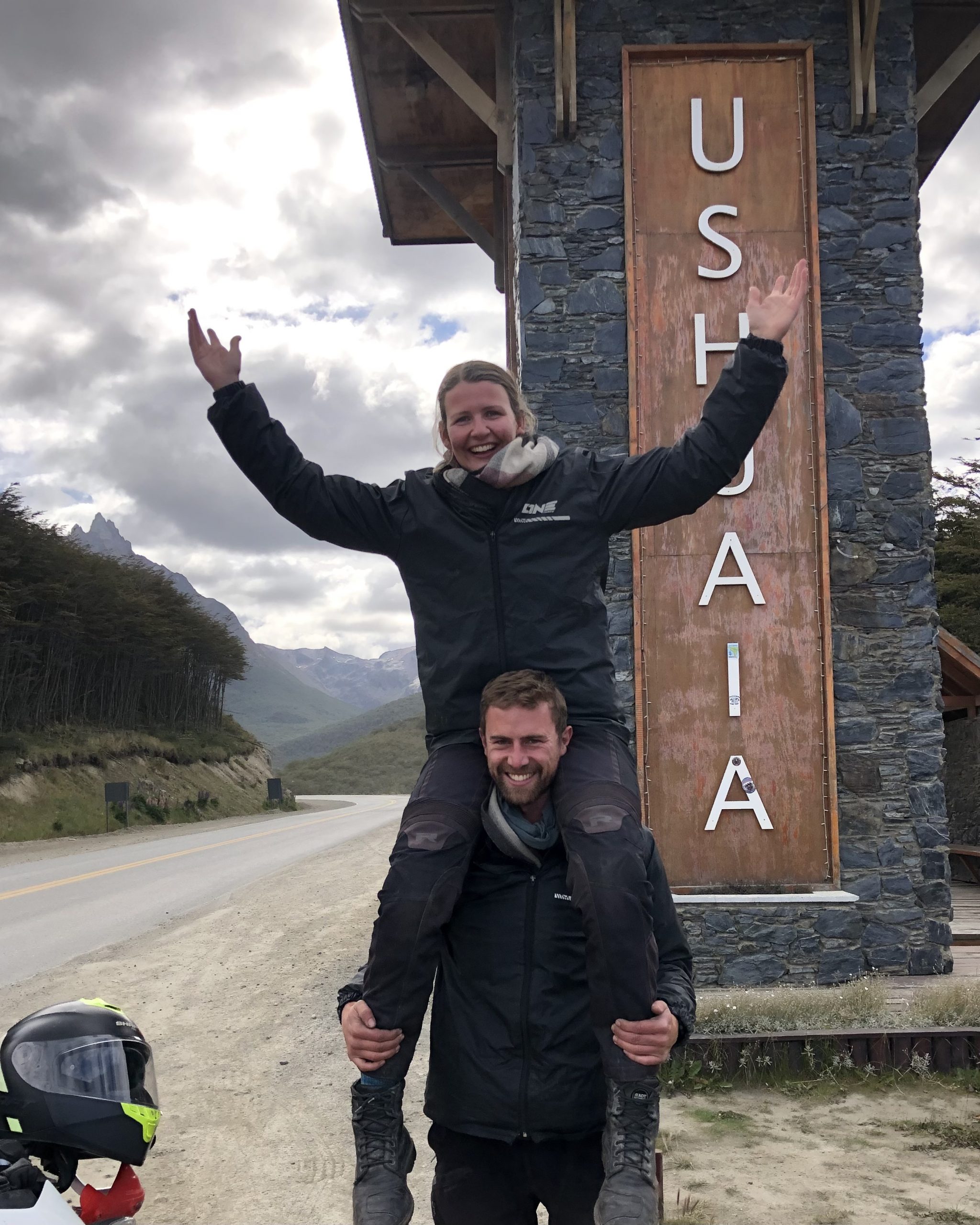 Zwei Motorradfahrer vor dem Ushuaia-Ortseingangsschild in Argentinien während Motorradreise durch Südamerika