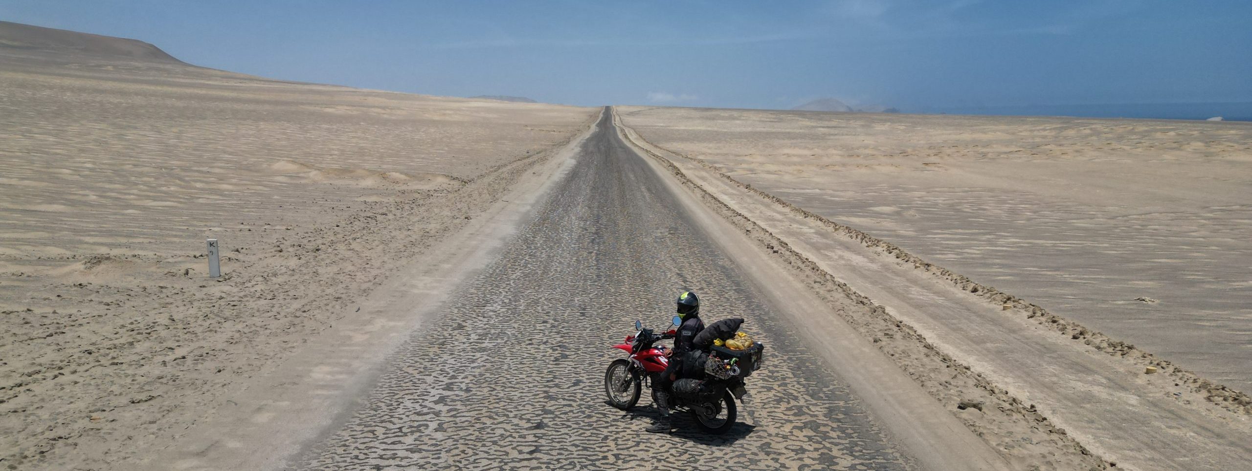 Drohnenaufnahme eines Motorrads in Sandwüste in Südamerika während Motorradreise