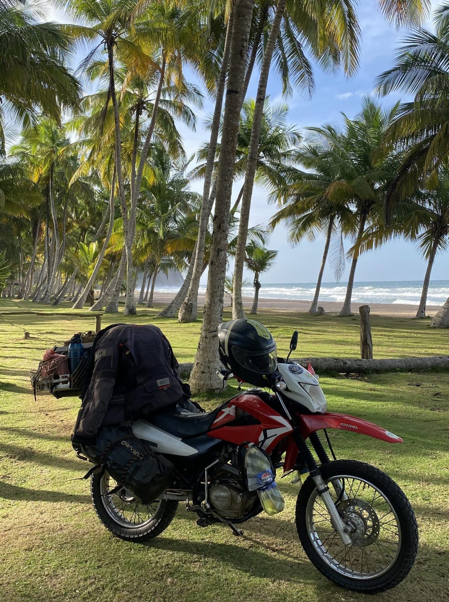 Motorrad an Palmenstrand in Kolumbien mit Meer im Hintergrund auf Motorradreise durch Südamerika