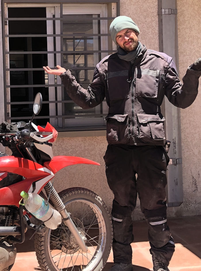 Motorradfahrer auf Motorradreise in Südamerika vor geschlossenem Grenzübergang in Bolivien mit Reiseenduro