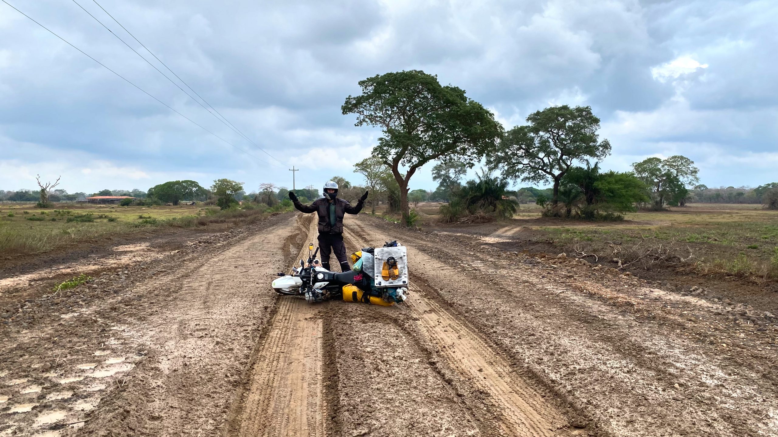Motorradfahrer steht hinter im Schlamm liegendem Motorrad in Brasilien auf Motorradreise durch Südamerika